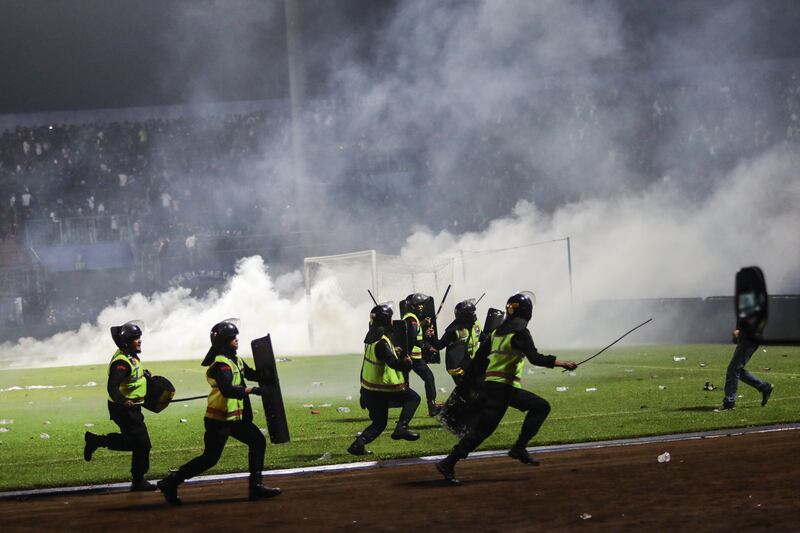 Police officers run as they try to stop fans from entering the pitch during a clash between fans at Kanjuruhan Stadium. EPA