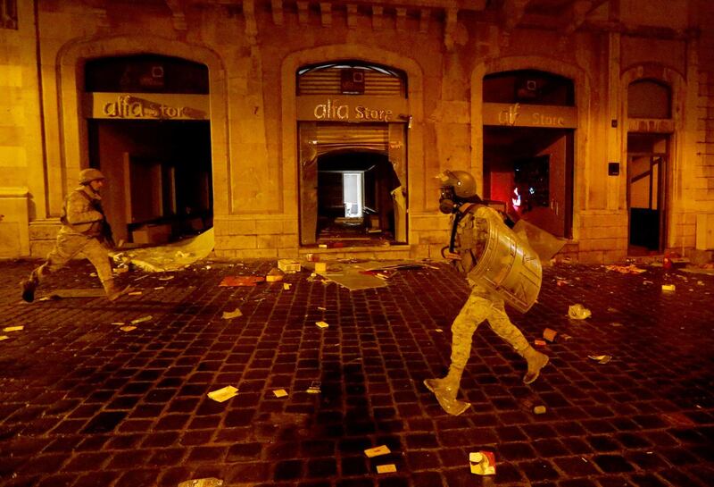 Lebanese army soldiers run past a damaged Alfa shop during a protest against a ruling elite accused of steering Lebanon towards an economic crisis in Beirut. REUTERS