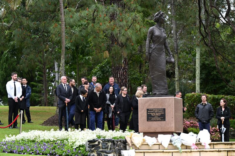 People gather around a statue of the queen at Government House in Brisbane, Australia. EPA