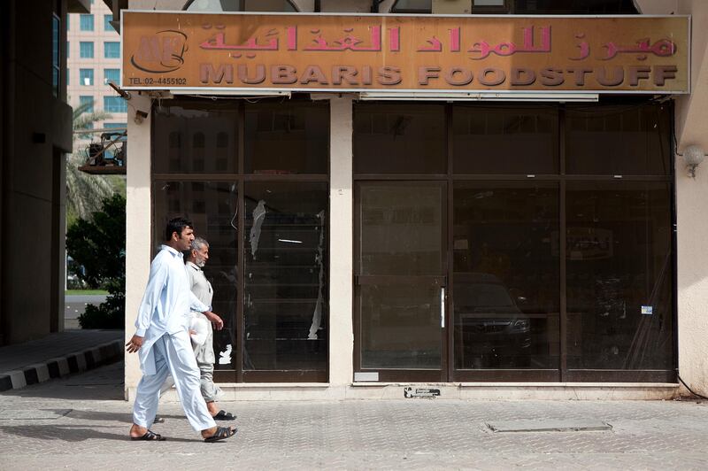 Abu Dhabi, United Arab Emirates, January 10, 2013: 
People walk by the Mubaris Foodstuff, a recently closed convenience store on Thursday, Jan. 10, 2013, in the city block between Airport and Muroor, and Delma and Mohamed Bin Khalifa streets in Abu Dhabi. 
Silvia Razgova/The National

