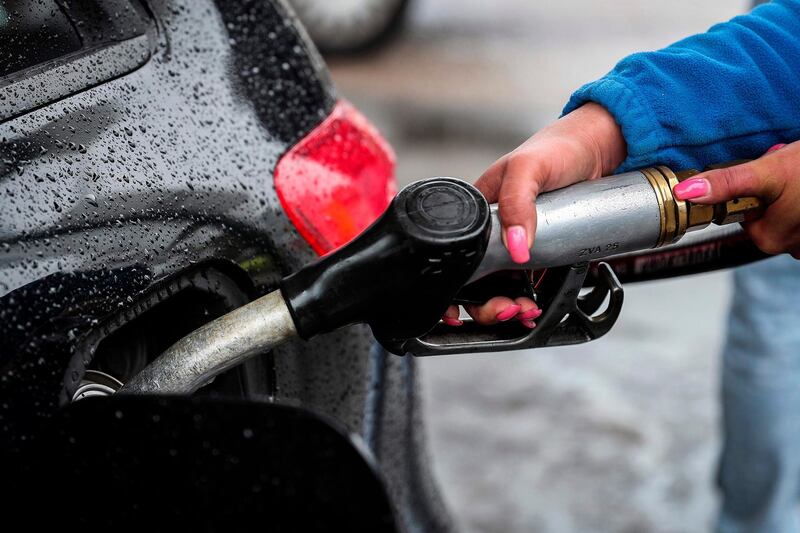 A local gas station worker fills a customer´s cars as people 
queue at a gas station on April 17, 2019 in Seixal, in the outskirts of Lisbon. Many Portuguese were queuing at the few gas stations where it was still possible to refuel despite the shortages caused by a strike of the fuel carriers.  / AFP / CARLOS COSTA
