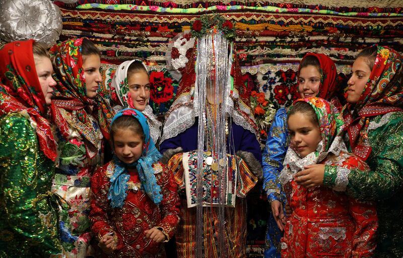 Bulgarian Muslim bride Dhzemile Lilova, 30, poses with friends and relatives in front of the dowry, wearing special make-up called 'ghelina' during her wedding ceremony in the village of Draginovo, Bulgaria. The traditional wedding ritual is held among Pomaks - Slavs who converted to Islam under Ottoman rule. The highlight of the ceremony is the painting of the bride's face, where in a private rite her face is covered in white face cream and decorated with gold flakes and colourful sequins. Stoyan Nenov / Reuters.