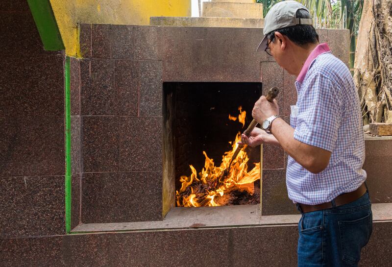 A pilgrim rakes the paper to ensure it is fully burned