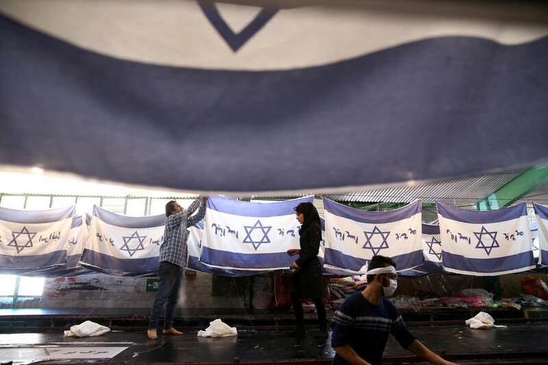 Iranian workers collect altered Israeli flags at a large factory that males US and Israeli flags for Iranian protesters to burn in Khomein City. West Asia News Agency via Reuters