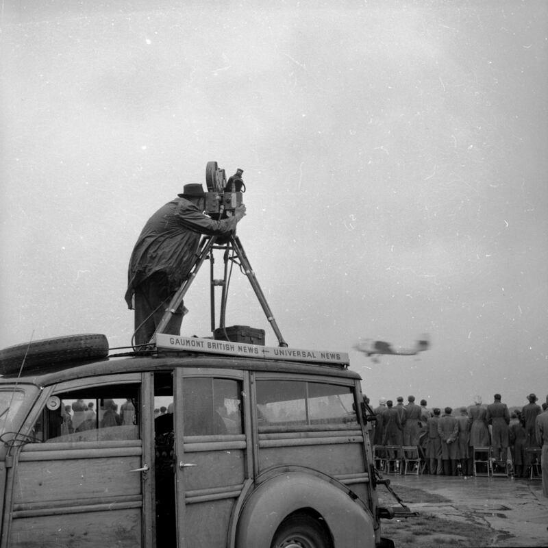 A cameraman stands on the roof of his estate car to get footage of the 1956 Farnborough Airshow. 