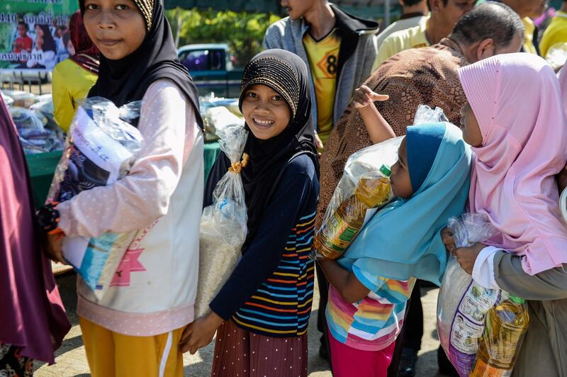 Thai Muslim girls carry bags of rice and food donated by the local government during a ceremony ahead of the Islamic holy month of Ramadan in the southern Thai province of Narathiwat. AFP