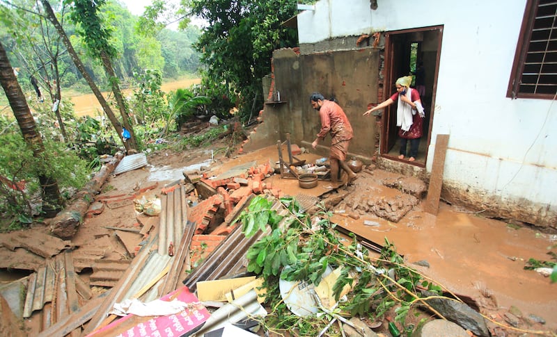 An Indian man clears mud from his home after heavy rain hits Kottayam in Kerala, causing a landslide. EPA