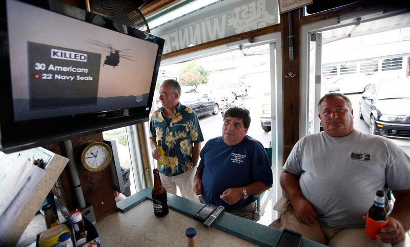 Virginia Beach residents Tom Hall, left, and Mark Janik, center, watch as news about the Navy Seal Team Six helicopter accident is displayed on a television at a bar in Virginia Beach , Va., Saturday, Aug. 6, 2011. The headquarters for the Navy Seal Team Six is located in Virgina Beach. (AP Photo/Steve Helber) *** Local Caption ***  Afghanistan Seals Virginia.JPEG-026b4.jpg
