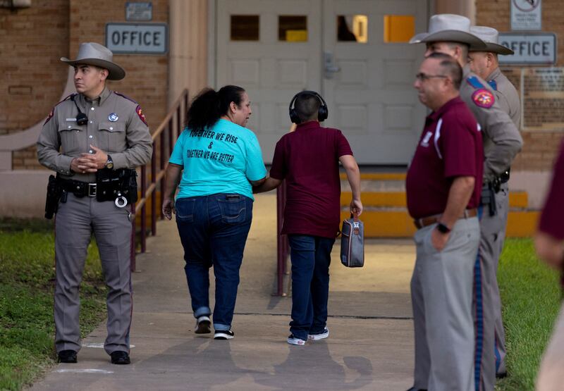 Texas Department of Public Safety officers and school personnel from Flores Elementary School greet pupils as they return after the summer break. Reuters
