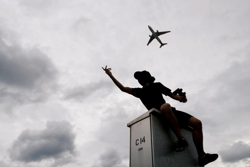 A plane flies over an anti-extradition bill protester as he demonstrates outside the airport in Hong Kong, China. Reuters