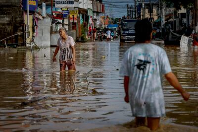 Residents wade through flooding caused by Super Typhoon Noru on Monday in San Miguel, Bulacan province. Getty 