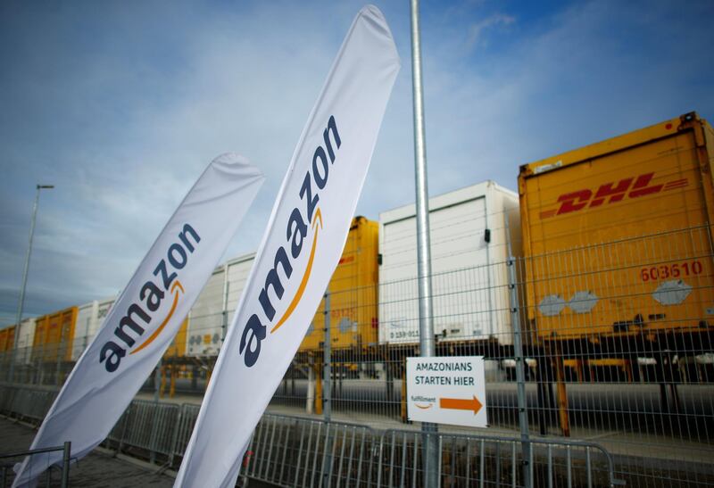 Flags with the logo of Amazon and trailers of German postal and logistic Deutsche Post DHL Group are pictured outside the new Amazon logistic center in Dortmund, Germany November 14, 2017. REUTERS/Thilo Schmuelgen