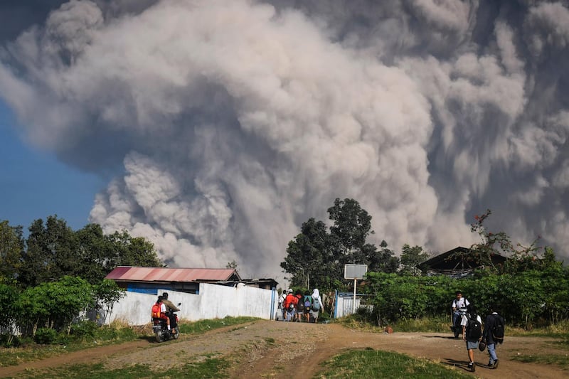 Indonesian students walk as Mount Sinabung erupts in Karo, North Sumatra, Indonesia. Mount Sinabung erupted on February 19, blowing volcanic ash more than 5,000 metres in the sky. Sinabung is one of the most active volcanos in Indonesia. It erupted in 2010 and since then killed 17 people in eruptions in 2014 and another nine people in 2016.  Sarianto Ojo Sembiring / EPA