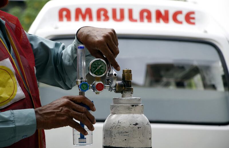 An aid worker of Alamgir Welfare Trust in Islamabad is fixing flow meter/ regulator at an oxygen cylinder before its delivery to a COVID-19 patient. Imran Mukhtar/ The National 