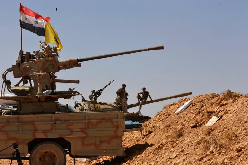 Syrian forces members stand on a tank next to vehicles waiting to transport Islamic State (IS) group members in the Qara area in Syria's Qalamoun region on August 28, 2017 as part of a deal between Hezbollah and IS fighters where the jihadists would leave to eastern Syria.
Syria's state news agency SANA, quoting a military source, confirmed Hezbollah and IS had agreed that "the remaining Daesh (IS) fighters will leave to eastern Syria". And a Lebanese military source told AFP the jihadist group would quit territory it held in eastern Lebanon.
 / AFP PHOTO / Louai Beshara