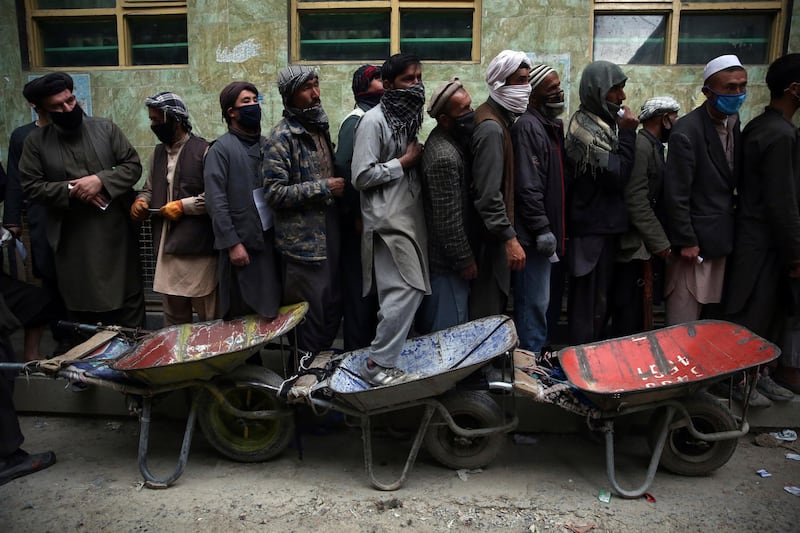 Daily-wage workers wait in line to receive free wheat donated by Afghan businessmen ahead of the upcoming holy fasting month of Ramadan in Kabul, Afghanistan, Monday, April 20, 2020. Muslims across the world are observing the holy fasting month of Ramadan, when they refrain from eating, drinking and smoking from dawn to dusk. (AP Photo/Rahmat Gul)