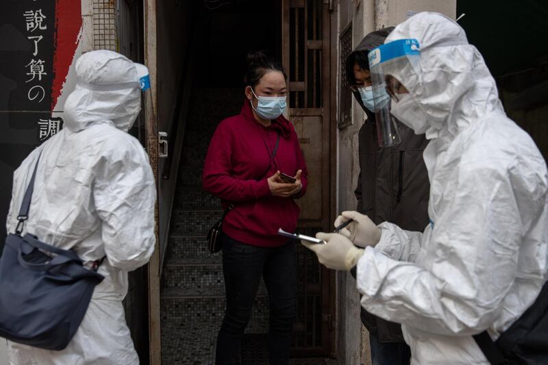 Civil servants check a local resident for her negative Covid-19 test results before allowing her outside, in the Jordan district in Hong Kong, China. EPA