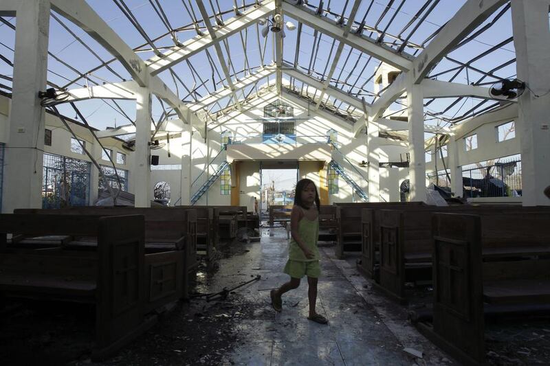 A girl walks through the destroyed Our Lady of the Holy Rosemary church as mass is delivered at a neighboring construction site in Palo, Philippines. Wally Santana /AP Photo