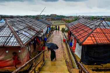 A Rohingya refugee girl shelters from the rain under an umbrella as she makes her way back home after collecting relief aid at the Kutupalong Rohingya refugee camp in Bangladesh's Ukhia district on August 24, 2019. / AFP / MUNIR UZ ZAMAN