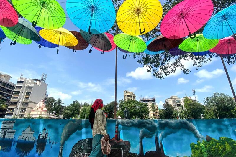 A woman walks under an art installation of colourful umbrellas as Covid-19 restrictions ease in Mumbai, India. AFP