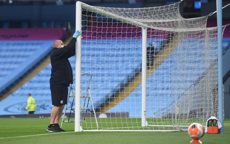 A member of staff disinfects a goal frame during half time as play resumes behind closed doors. Reuters