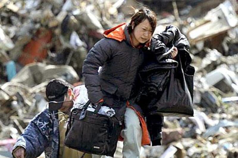 A woman carries belongings she collected from a house swept by a tsunami at Rikuzentakada, in northeastern Japan.