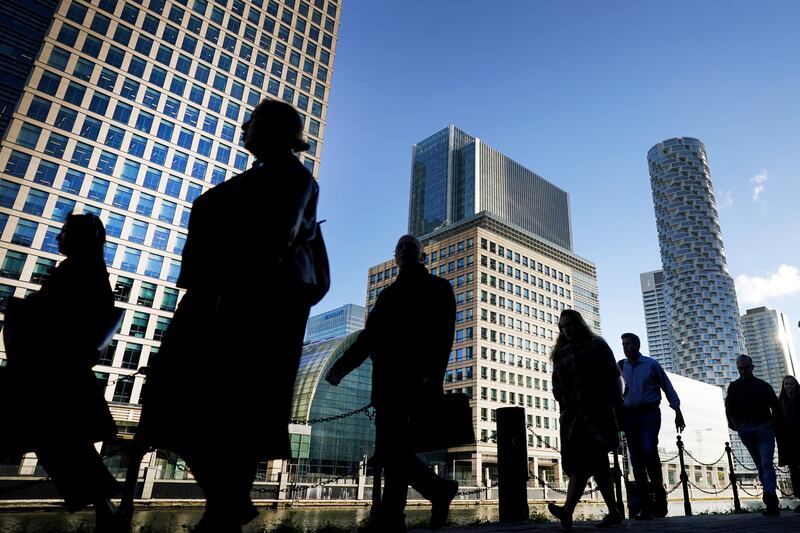 Commuters walk through Canary Wharf in London. PA