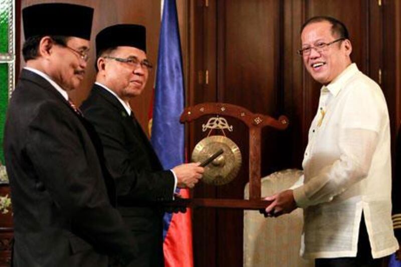 Moro Islamic Liberation Front (MILF) Chairman Murad Ebrahim, centre, signs the peace accord with Philippines president Benigno Aquino III.