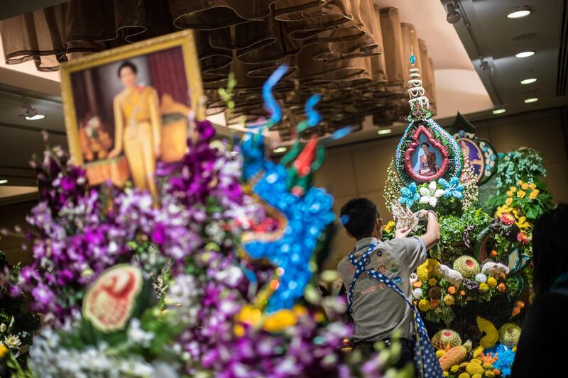 A Thai man helps put together an elaborate decoration with carved fruits and vegetables adorned with images of Thai Queen Sirikit, during a fruit and vegetable carving competition in Bangkok. Robert Schmidt / AFP