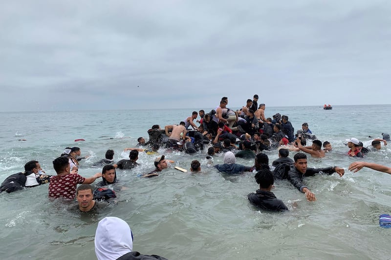 Migrants manage to grab onto a boat of the Moroccan authorities near the coast of Fnideq in an attempt to cross over to Ceuta. EPA