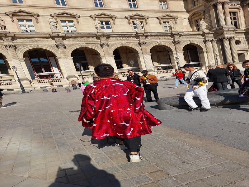 A man in an amazing woven coat,  outside Louis Vuitton.