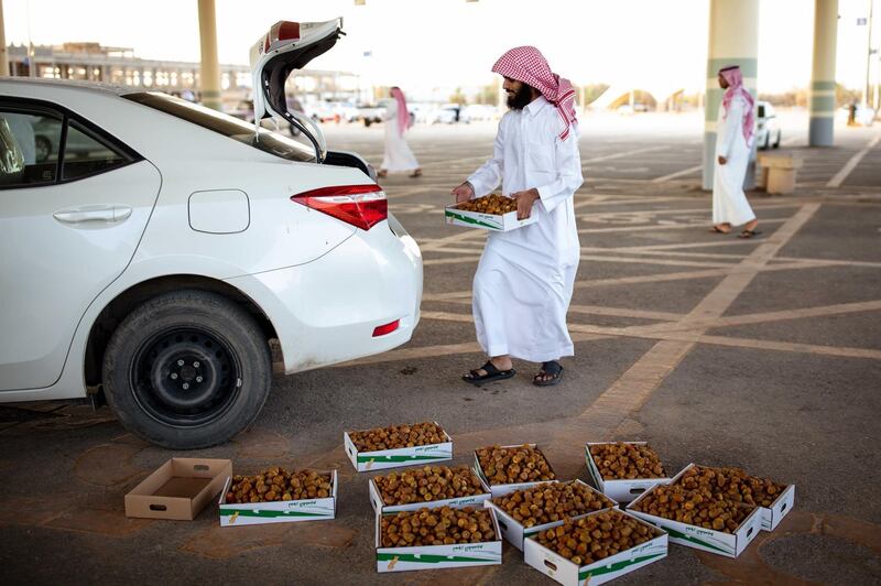 A customer loads boxes of dates into a vehicle at a local market in Buraidah, Saudi Arabia. Bloomberg