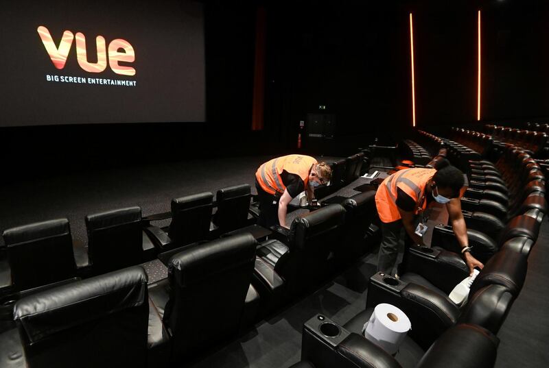 Staff members clean seats at Vue Cinema in Leicester Square as it reopens in London. Reuters