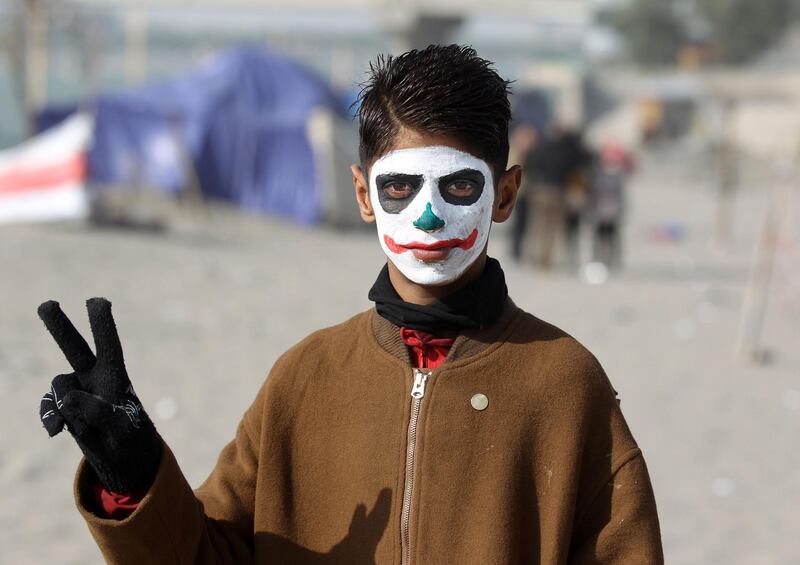 TOPSHOT - An Iraqi protester wearing face-paint imitating DC comic and film character "The Joker" poses for a picture near the sit-in by Senak bridge over the Tigris in the capital Baghdad on December 25, 2019.  / AFP / AHMAD AL-RUBAYE
