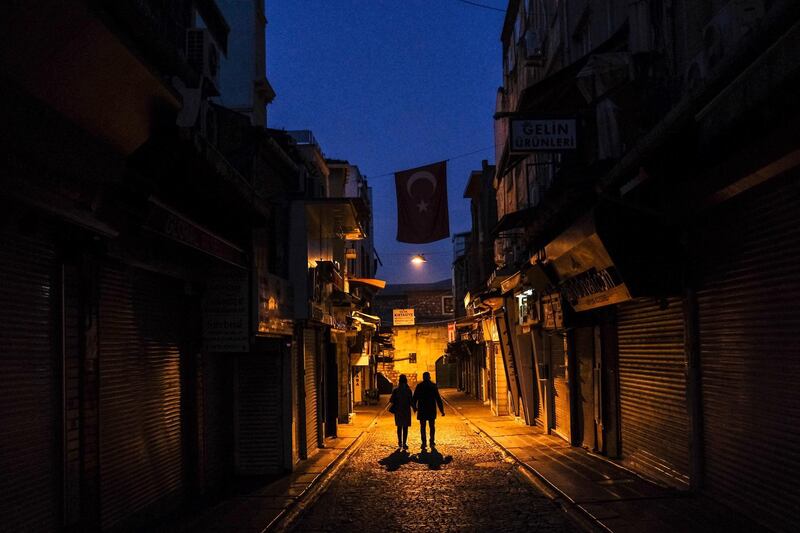 Tourists walk under the Turkish flag at the old city local bazaar during the lockdown in Istanbul. EPA