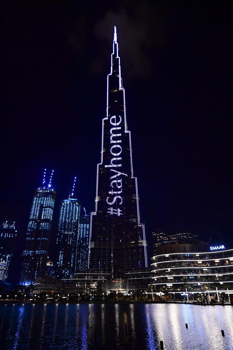 A picture shows Dubai's Burj Khalifa lit up with a message "Stay Home" urging residents to comply with the preventive measures amid the coronavirus COVID-19 pandemic, on March 24, 2020. / AFP / Giuseppe CACACE
