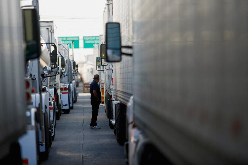 A man is seen outside of his truck as he waits in a long queue to cross into the US. Reuters