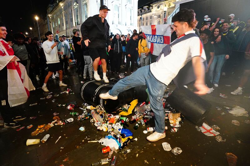 An England fans kicks a litter bin in Piccadilly Circus, London, after his team lost on penalties to Italy.