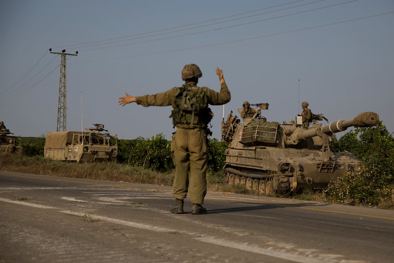An Israeli soldier directs armoured vehicles heading towards the border with the Gaza Strip. Getty Images