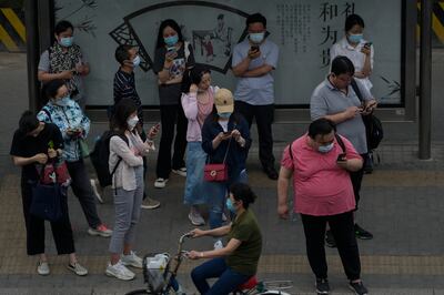 Commuters browse their smartphones as they wait for their buses in Beijing. Concerns about technology are more about access and knowledge than actual harm. AP