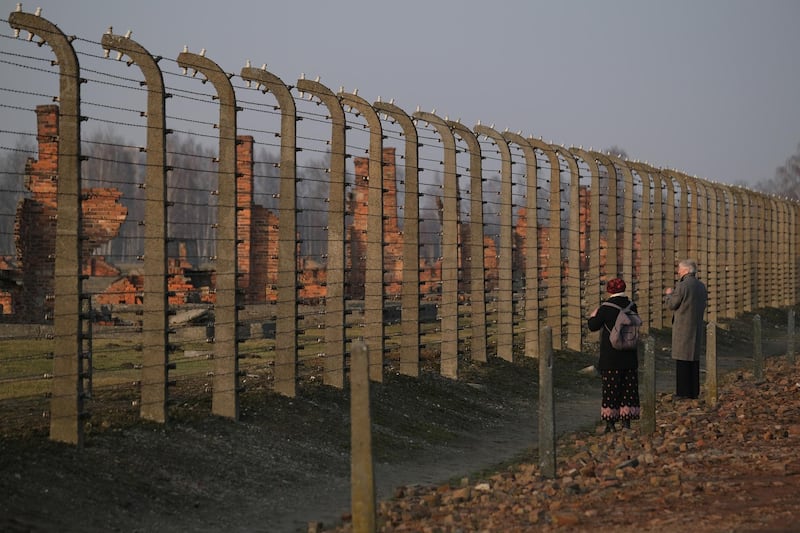 Visitors look through barbed wire towards the remains of prisoner barracks at the former Auschwitz-Birkenau German concentration camp near Oswiecim, Poland. Getty Images