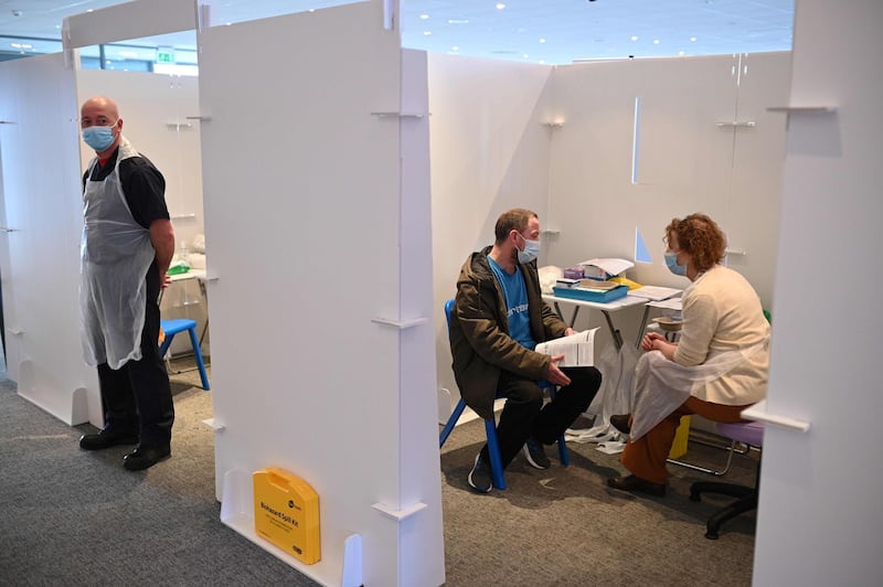 A vaccinator talks with a patient in a booth at the vaccination centre set up at Chester Racecourse. AFP