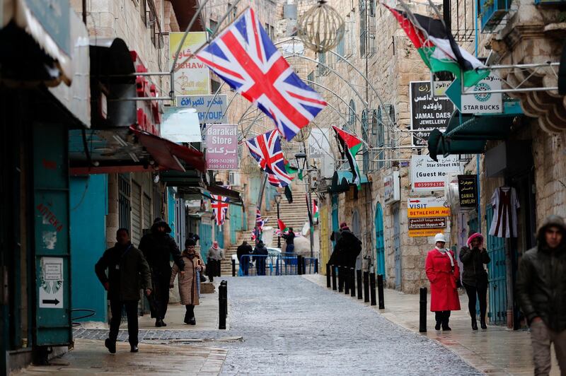 People walk down a street lined with the Union Flag in anticipation of the arrival of Prince Charles for a visit to the Mosque of Omar. EPA