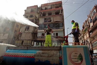 Men stand on a truck as they sanitize a street as a precaution against the spread of coronavirus disease (COVID-19), during a media tour organised by Hezbollah officials, in Beirut's southern suburb, Lebanon March 31, 2020. Picture taken March 31, 2020.  REUTERS/Aziz Taher