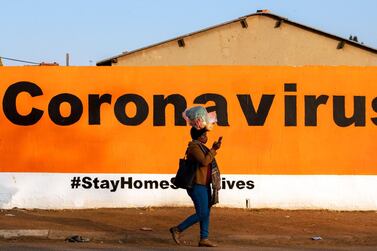 A South African woman wearing a face mask whilst carrying a bag of vegetables atop her head, walks past a wall with Covid-19 in Soweto. South Africa’s debt levels will exceed 100% of its GDP in 2025. AP Photo