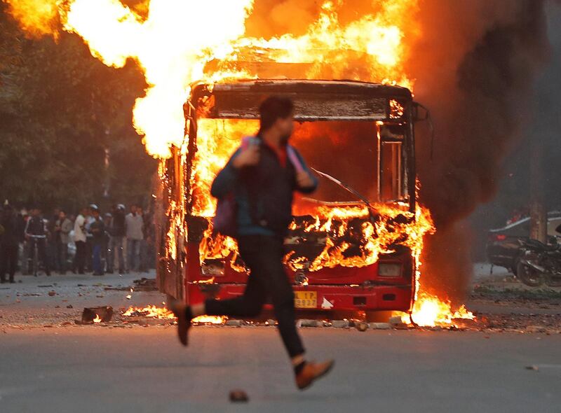 A man runs past a burning bus that was set on fire by demonstrators during a protest against a new citizenship law, in New Delhi, India, December 15, 2019.  REUTERS/Adnan Abidi TPX IMAGES OF THE DAY