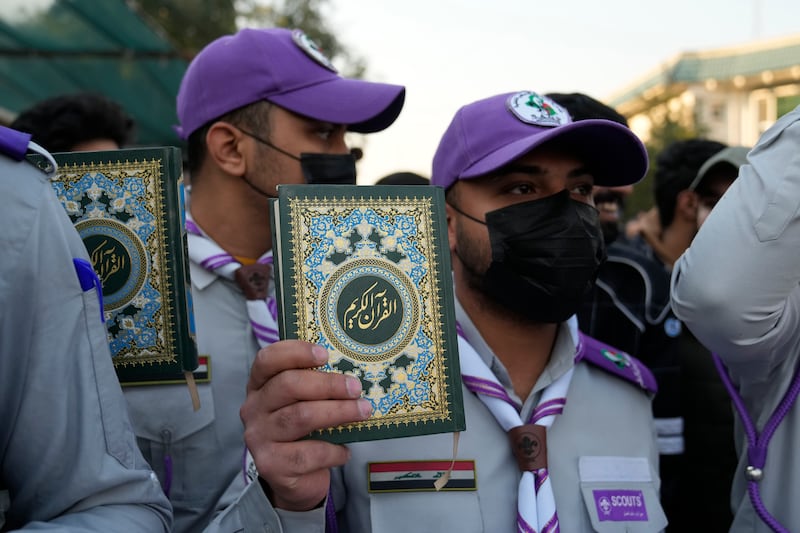 Protesters in Baghdad hold up the Quran. AP