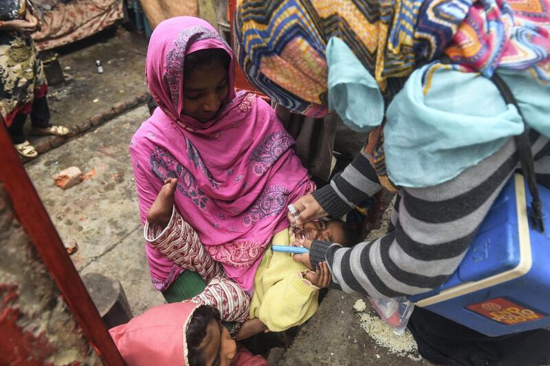 A Pakistani health worker administers polio vaccine drops to a child during a polio vaccination campaign at a slum area in Lahore on January 22, 2019. (Photo by ARIF ALI / AFP)