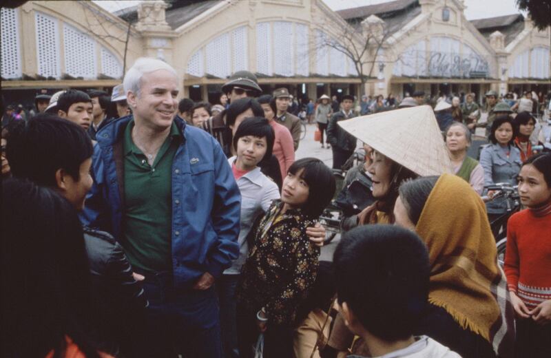 American politician Senator John McCain (center, in blue jacket and green shirt) talks with people on a crowded street during the filming of a CBS Reports Special entitled 'Honor, Duty and a War Called Vietnam,' Hanoi, Vietnam, March 6, 1985. (Photo by CBS Photo Archive/Getty Images)