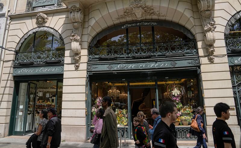 People walk past the Guerlain boutique at the Champs-Elysees avenue in Paris